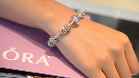 A woman's hand wearing a Pandora charm bracelet.