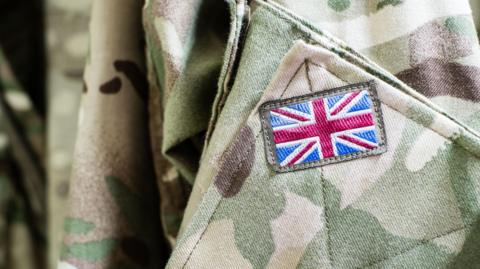 Close up photograph of a Union Flag embroidered patch on the shoulder of army fatigues.