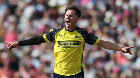Sonny Baker has his arms stretched out after taking a wicket for Hampshire