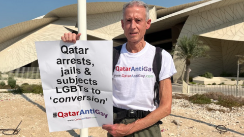 Peter Tatchell holds a poster with the hashtag 'Qatar Anti Gay'