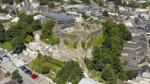 Haverfordwest Castle surrounded by green trees and houses from an aerial view