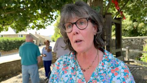 woman in blue flowery top wearing glasses