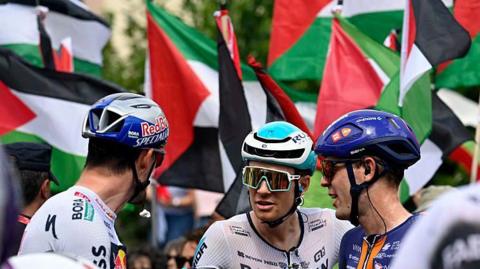 Riders prepare to compete at the Vuelta a Espana as pro-Palestine protests go on in the background