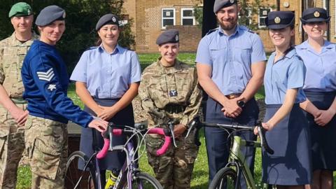 RAF Digby staff standing in front of a Lancaster bomber with two holding onto bikes