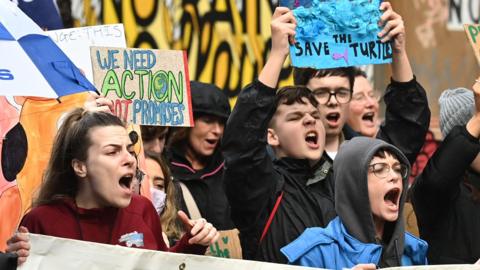 Protesters chant and hold placards at the climate change rally in Belfast