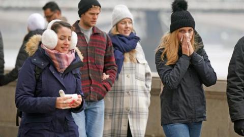 These Londoners are well wrapped up as they walk along the Thames