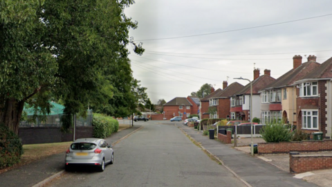 A street scene with houses on one side of the road and trees on the other