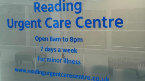 A glass window outside the centre which says in blue typeface: 'Reading Urgent Care Centre/Open 8am to 8pm/7 days a week/For minor illness".