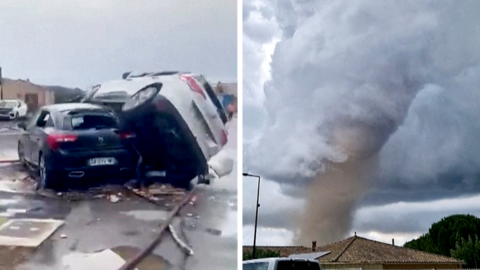 A tornado is seen spinning above a house in the clouds, with two cars on top of each other on the right.