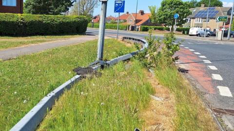 A crash barrier bent out of shape on a road bend.