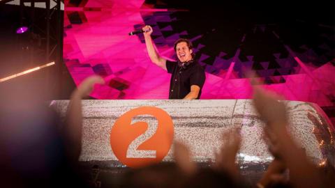 Vernon Kay stands on stage behind the decks at Radio 2 in the Park