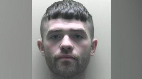 A mugshot of a man called Findlay Mackay. He has short dark hair which has been shaved round the sides but left slightly longer on top. He has a trimmed dark beard.