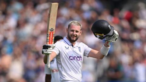 England's Gus Atkinson raises his bat and helmet to celebrate hitting a century