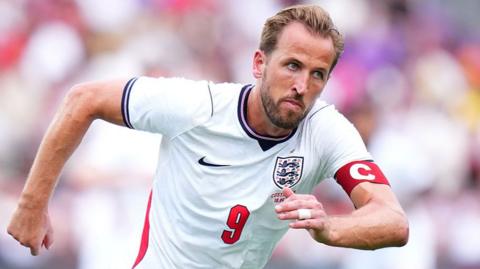 Harry Kane running in white England shirt with number 9 on front