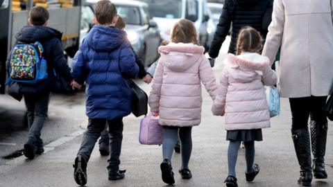 Four children and an adult walking