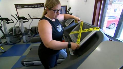 Lesley Harper tapes off treadmills in her gym