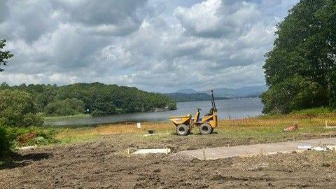 Cherry picker on ground next to lake