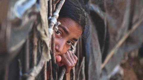 Girl looking out from a makeshift shelter