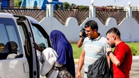 A Sudanese woman (centre) carrying her baby is escorted into a vehicle in Syria's north-eastern city of Qamishli, after she was handed over to Sudanese diplomats by Kurdish officials. Photo: 20 September 2018