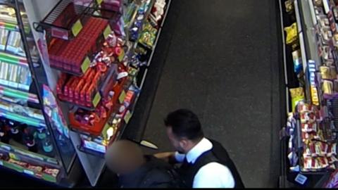 CCTV image of PC Younger tackling the suspect inside a shop.