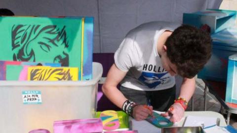 Anonymous boy making craft on a market stall