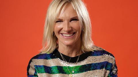 Jo Whiley smiling broadly in front of a bright orange background