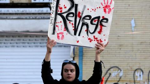 An Iranian mourner holds a placard during the final stage of funeral processions for the general Qasem Soleimani