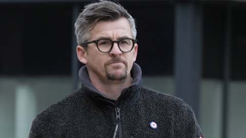 Joey Barton outside Liverpool Crown Court in a fleece and glasses. 