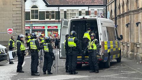 Humberside Police officers dressed in riot gear standing behind a police van