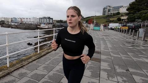 Issy Hart out on a run along Plymouth waterfront on an overcast day