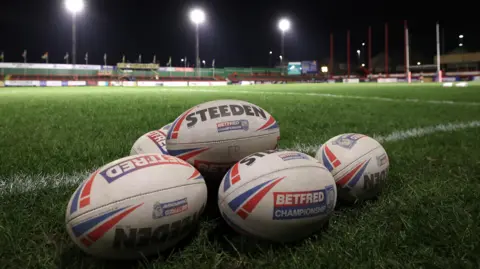 A collection of Championship rugby league balls on the side of a pitch