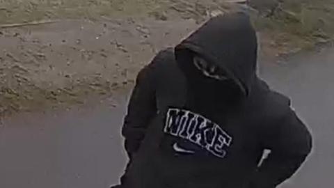 Person wearing a black hoodie and mask.