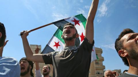 Syrian protesters wave their national flag as they demonstrate against the regime and its ally Russia, in the rebel-held city of Idlib on September 7, 2018