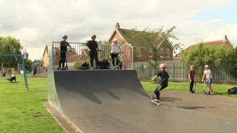 Kids scootering and skateboarding in a skate park