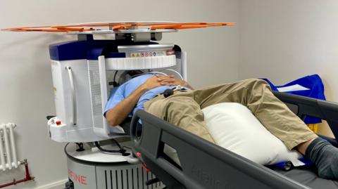 A man lying on his back on a medical trolley with his head inside a scanner