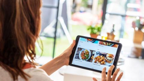 A woman looking at the HelloFresh app on a tablet