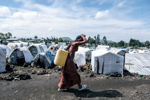 An internally displaced person carries water to her shelter in the Shabindu camp on 9 April 2024