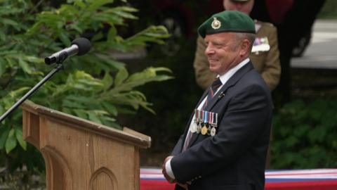 Jason Cox wearing his royal marines uniform stood behind a lectern 