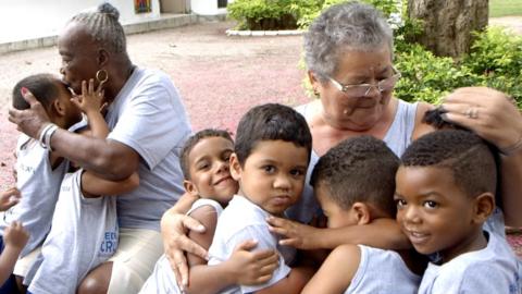 Elderly women hug children from the City of God favela
