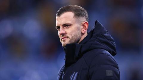 Jack Wilshere in a navy blue coat with a hood