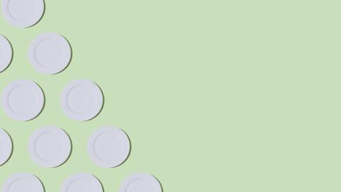 White dinner plates arranged in diagonal lines on a mint green background