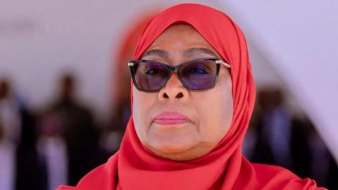 A close-up of Samia Suluhu Hassan wearing dark glasses and a red headscarf.