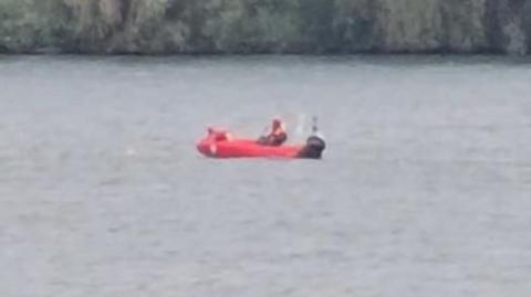 A blurry, zoomed-in image of a red rescue boat on open water. 