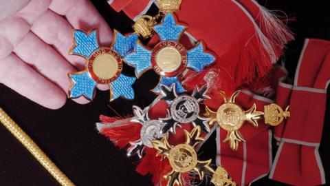 Blue, gold and silver medals are placed on a black cloth with red bows. 