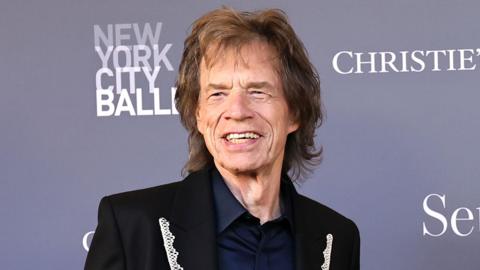 Mid-shot of Sir Mick Jagger, wearing a lace lapelled suit jacket