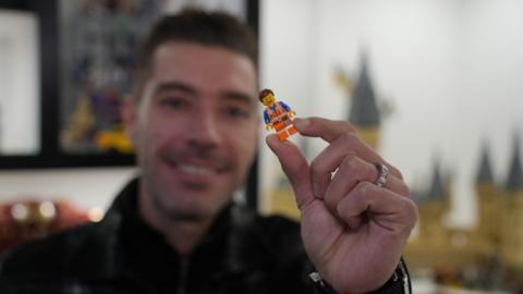 Darren Ambrose blurred, holding up a small yellow Lego man