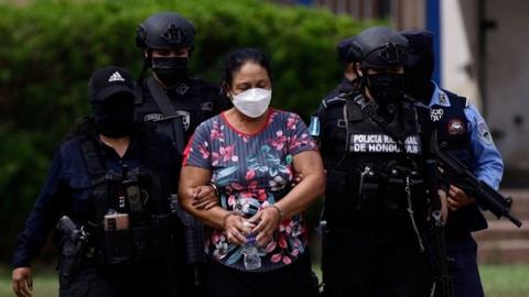 Police officers escort cartel leader Herlinda Bobadilla following an extradition request for her and her sons by the United States, in Tegucigalpa, Honduras May 15, 2022.