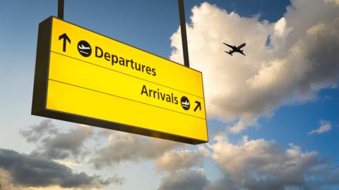 Neon yellow Heathrow Airport sign with plane taking off in the background