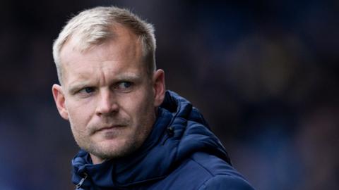 Oxford United manager Liam Manning looking tense during a League One game.