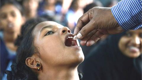 An Indian teacher poses for a photograph while handing out deworming tablets to students during National Deworming Day at a government high school in Hyderabad on August 10, 2016